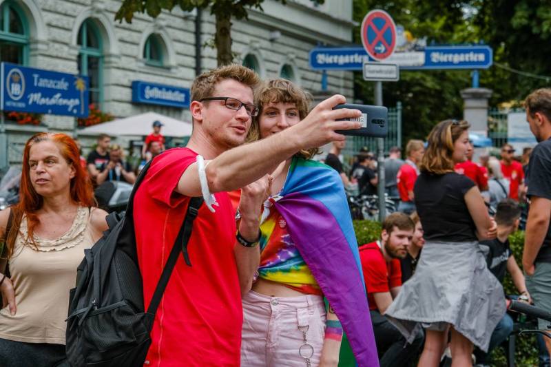 Ein Ungarn Fan fotografiert sich mit einer jungen Frau mit Regenbogenflagge. Ungarische Fußballfans treffen sich am Wienerplatz in München. Unter den meist friedlcihen Fans waren auch einige Ultras der Carpathian Brigade. (Foto: Thomas Vonier)