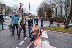 6 Aktivist:innen der Letzten Generation kleben sich an der Ampel Plinganserstraße Ecke Sylvensteinstraße auf die Straße und blockieren über eine Stunde lang den Verkehr, der sich auf dem Mittleren Ring staut.